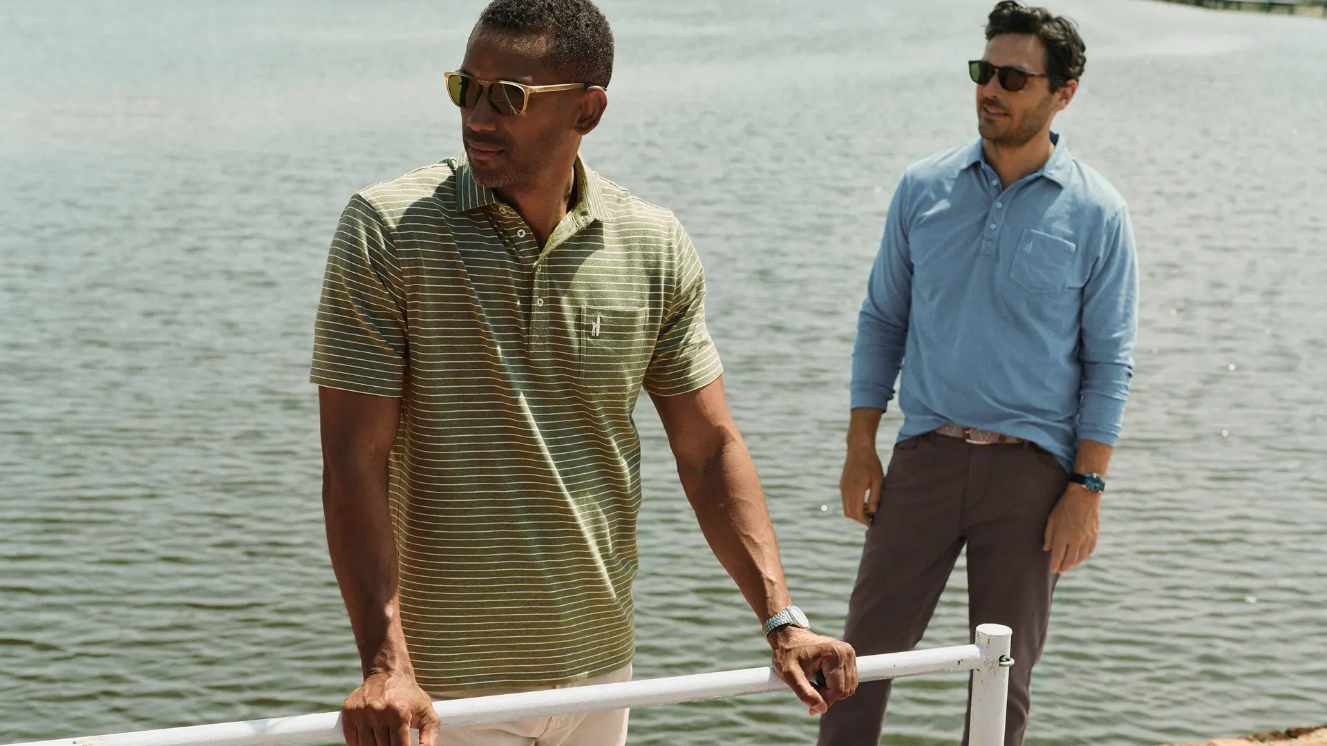 Two men dressed in cotton Johnnie-o polos while standing on a dock
