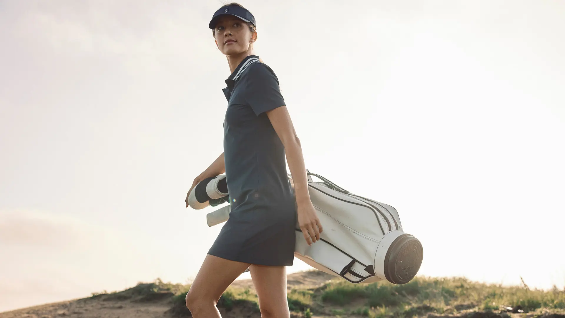 Woman wearing a performance polo golf dress and visor