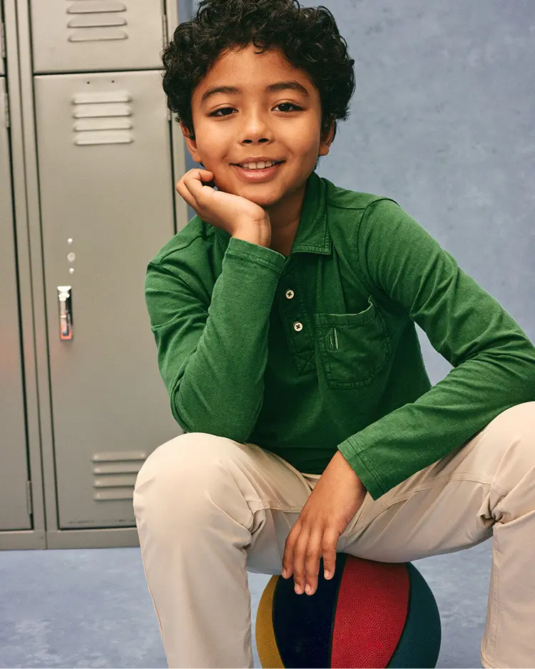 Boy wearing a green long-sleeve cotton polo and khaki pants at school
